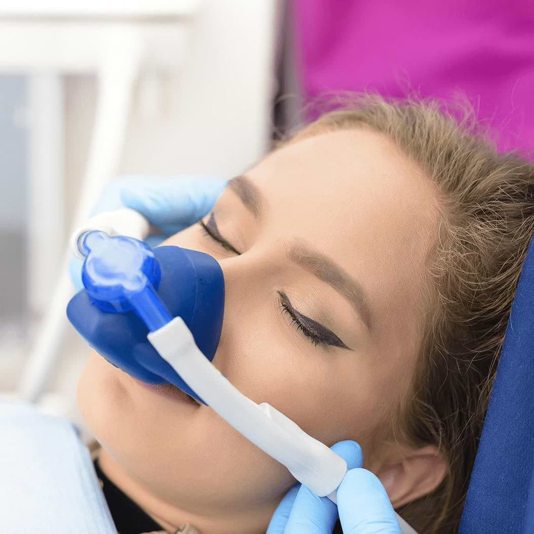 Woman with eyes closed and wearing a nasal mask in dental chair