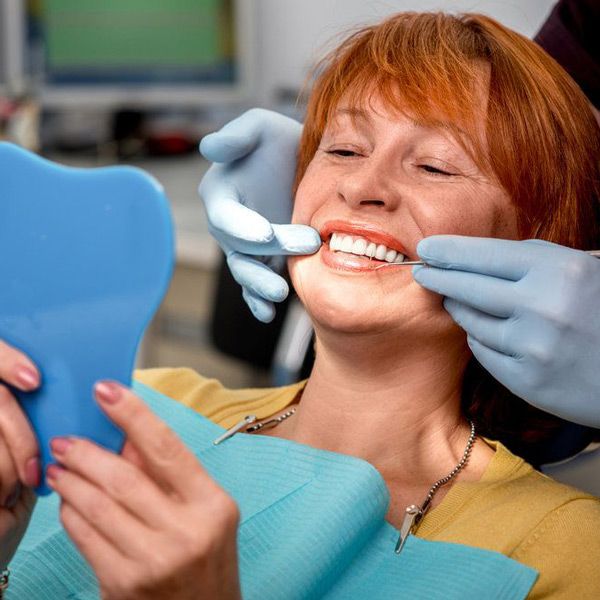 Woman smiling into a handheld mirror